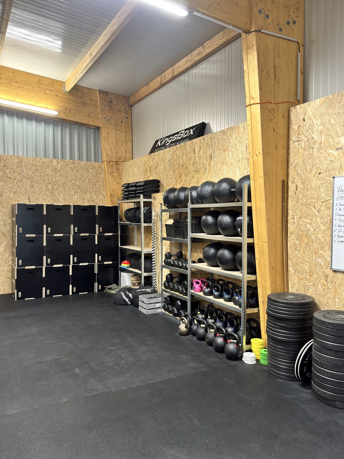 Le matériel rangé : caisses de saut, kettlebells, wall balls, haltères et disques olympiques.