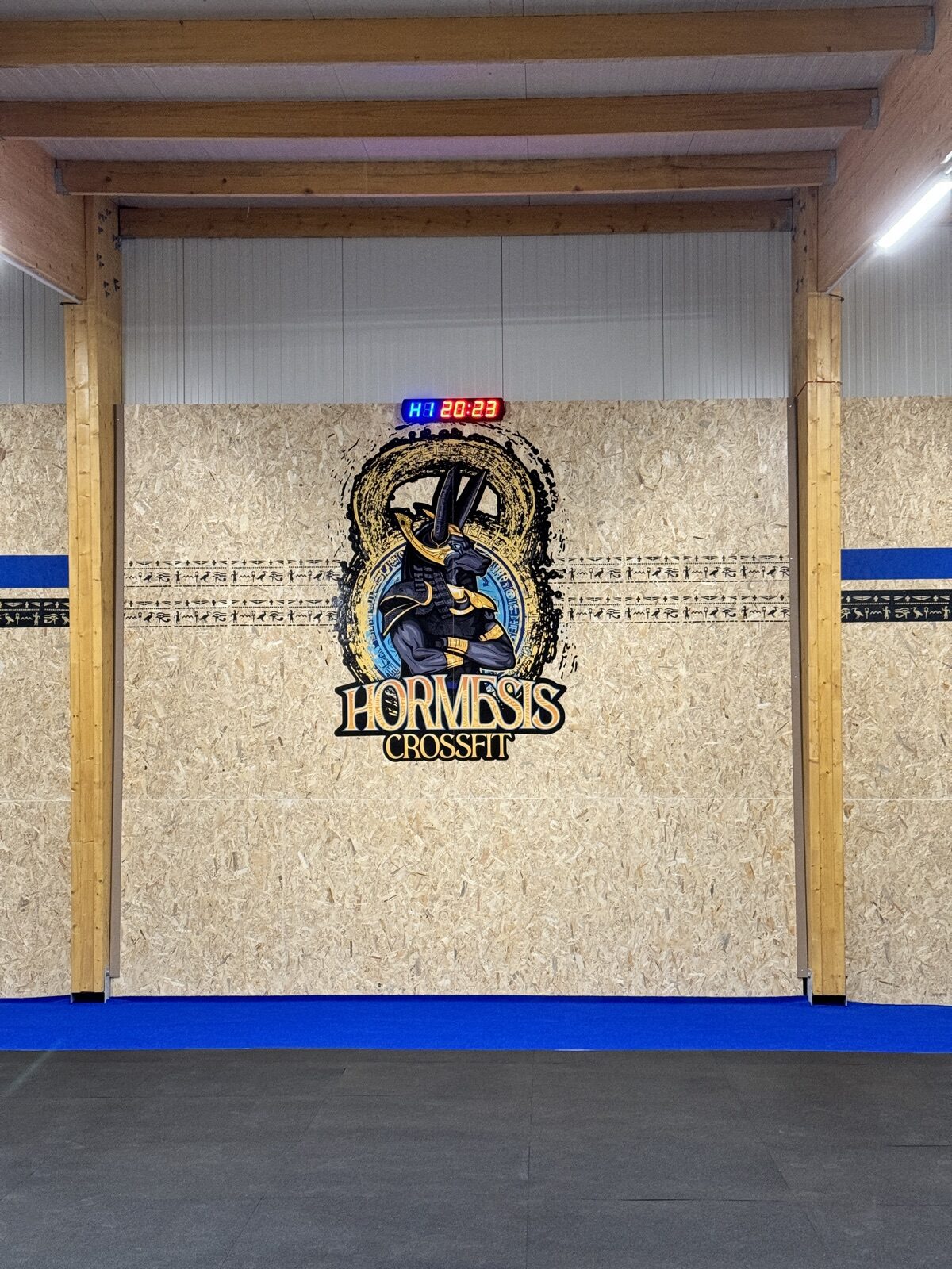 Le mur au logo CrossFit Hormesis, surmonté du chronomètre de la salle.