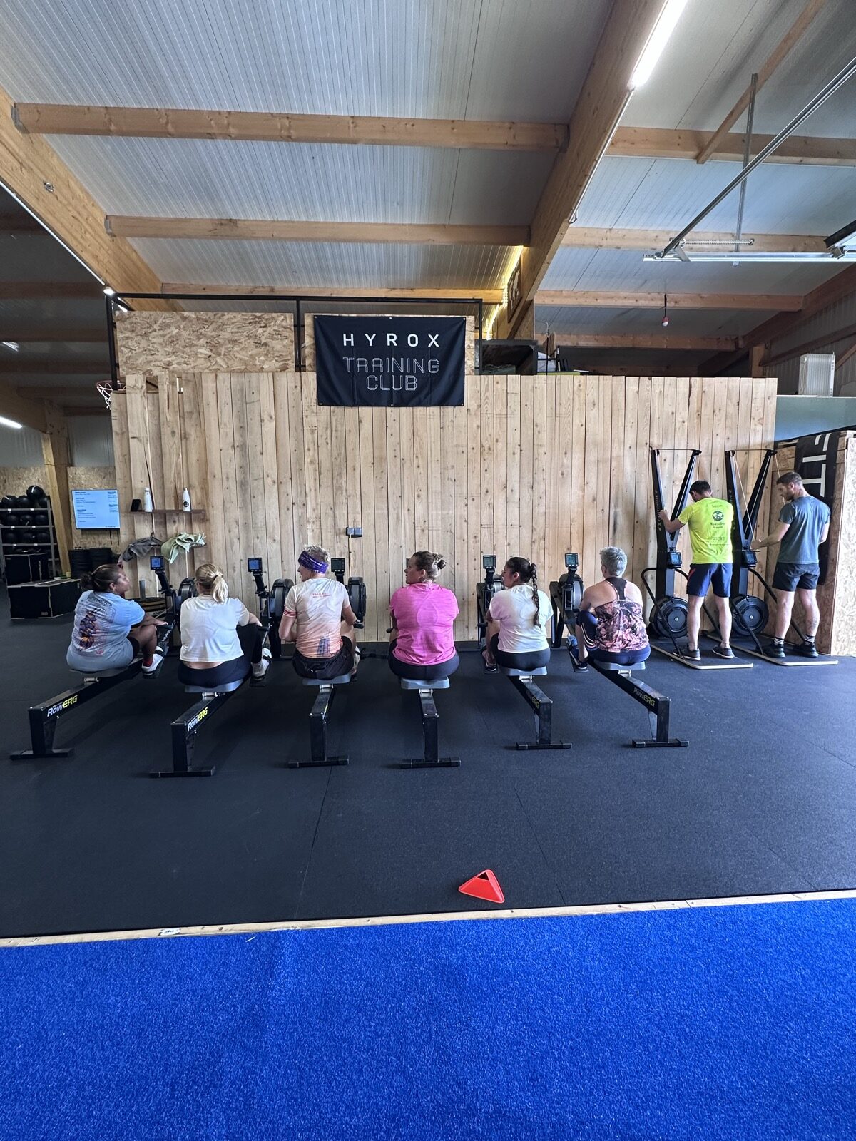 Un cours Hyrox : six adherentes aux rameurs sous la banniere Hyrox Training Club