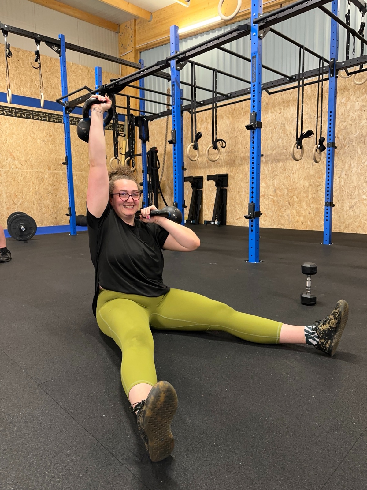 Une adherente souriante avec deux kettlebells apres son WOD